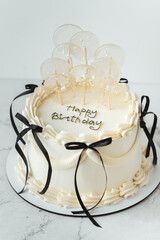 Delicate lambeth style birthday cake with white cream cheese frosting decorated with cream tracery and black happy birthday text on top. White background