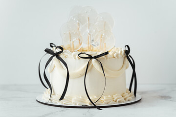 Delicate lambeth style birthday cake with white cream cheese frosting decorated with cream tracery and black happy birthday text on top. White background
