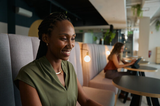Smiling young black businesswoman in smart casual working in office lobby