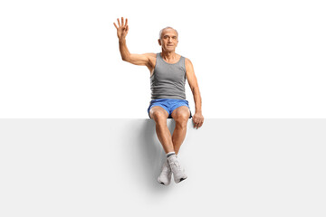 Elderly man in sportswear sitting on a blank panel and waving