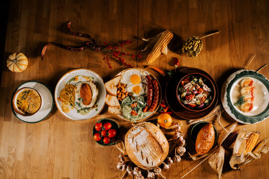 Breakfast spread with various dishes and fresh ingredients on a wooden table in a cozy setting