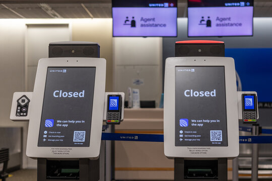 SAVANNAH, GEORGIA, USA, NOVEMBER 9, 2025: Two self-service check-in kiosks for United Airlines display a "Closed" message, with digital screens showing "Agent assistance" above them in the check-in ar