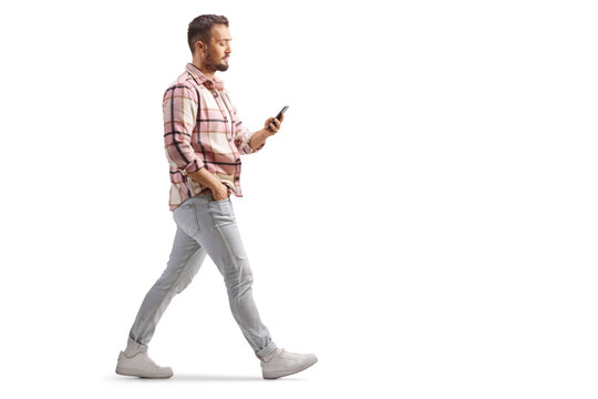 Full length profile shot of a guy in checkered shirt holding a smartphone and walking