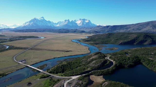 Torres del Paine, Chile: Orbit aerial drone view of Serrano river and the road at the entrance of Torres del Paine National park of Patagonia, Chile with Cordillera del Paine on a sunny day.