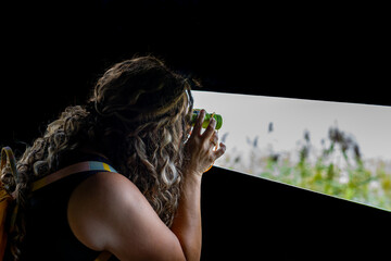 Young female tourist observes flowers, birds and bees with binoculars from an observation hut