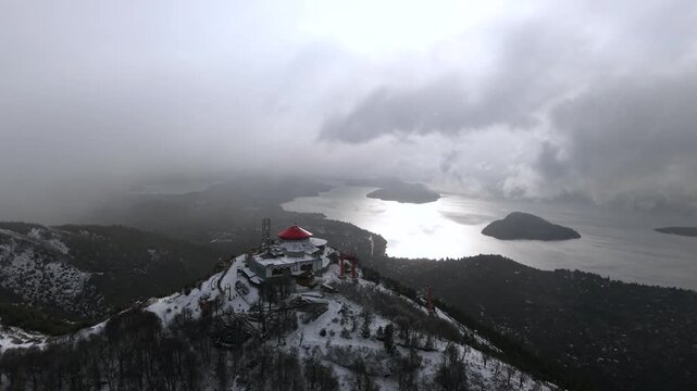 Snowy landscape of Cerro Otto with Nahuel Huapi Lake and cloudy mountains in Bariloche, Patagonia, Argentina.