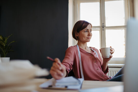 Female designer having coffee break during work.
