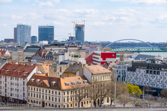 Bratislava cityscape featuring traditional and modern architecture. The image captures a mix of historical rooftops and contemporary skyscrapers, showcasing the iconic bridge and urban development - Powered by Adobe