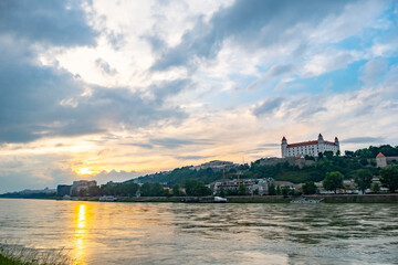 Fototapeta premium Scenic view of Bratislava Castle at sunset, overlooking the Danube River. Captures the iconic castle in Slovakia with a dramatic sky, blending historical architecture with natural beauty.