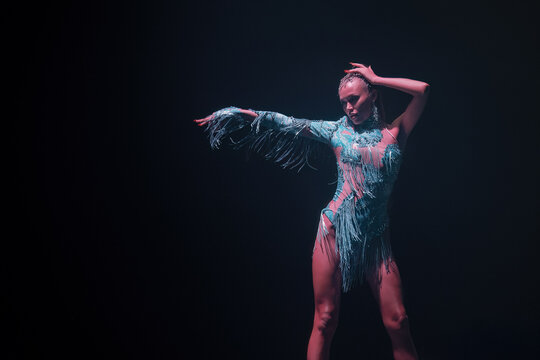 Elegant gogo dancer striking a powerful pose under soft teal stage light—confidence, glamour and nightclub vibe; horizontal frame with wide left-side negative space for copy.