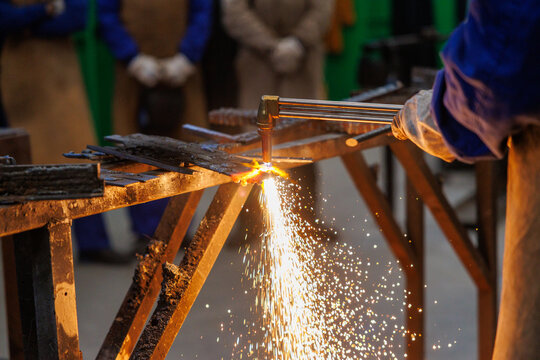 Artisan cutting metal with oxy-fuel torch creating sparks