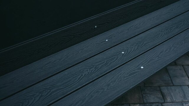 close-up dark composite decking planks screws, textured wood grain, patio edge over pavers, minimalist urban