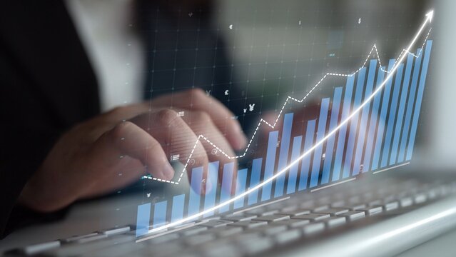 A business professional is engaged in data analysis, with a digital graph overlay on a keyboard, symbolizing growth and success in contemporary finance and analytics. Copula - Powered by Adobe