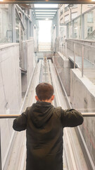 A toddler boy looks at the elevator mechanism in a transparent cable car. Concept of modern technology, child development