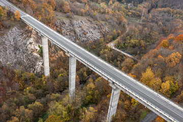 Aerial view of big viaduct of highway over the river in the mountain at autumn