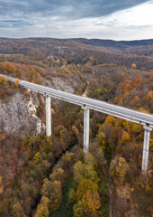 Aerial view of big viaduct of highway over the river in the mountain at autumn