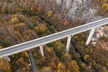 Aerial view of big viaduct of highway over the river in the mountain at autumn