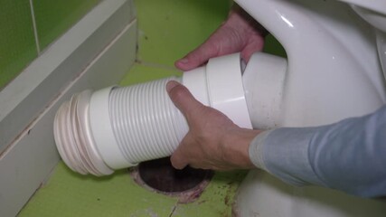 installing toilet corrugation, hands of a plumber installing a new corrugation to the toilet and connecting it to the sewer