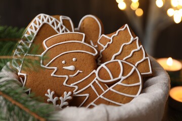 Christmas treat. Tasty gingerbread cookies in basket and decor on background with blurred lights, closeup. Bokeh effect