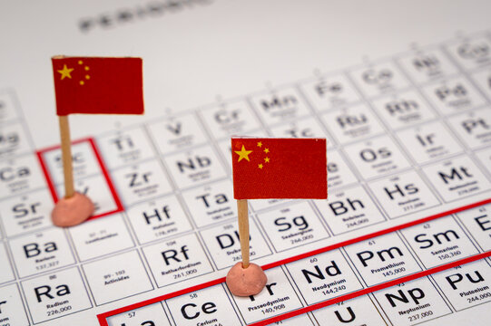 China flags marking critical rare earth elements on a periodic table, representing global resource control, trade wars, and economic dominance in technology and supply chains