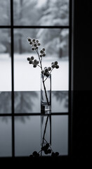 Elegant black and white still life of a frosty winter berry branch in a vase, reflected on a table. A minimalist and serene scene with a snowy window background, evoking quiet contemplation