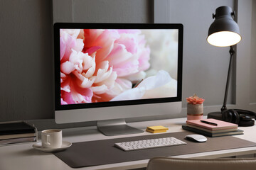 Stylish workplace with computer and grey mat on white desk in office