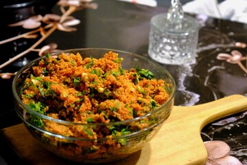 An image of kısır made with homemade bulgur in a glass bowl. Lettuce, green onions, and parsley are added to the kısır. Traditional Turkish food. Vegan diet. Snack plate.