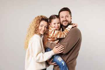Portrait of happy family hugging on grey background