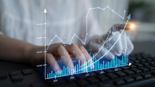A focused data analyst interacts with financial graphs while typing on a keyboard, representing modern technology use in business analytics and performance assessment. Scalp - Powered by Adobe