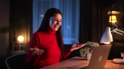 Smiling young woman having an online video call from home at night. Friendly communication, remote meeting, warm cozy lighting, laptop screen glow - Powered by Adobe