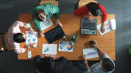 Top view of skilled business team looking financial chart while planning marketing strategy. Group of diverse people working laptop to analysis data and writing report at meeting room. Convocation.
