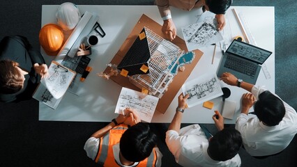 Top view of manager handed blueprint to professional engineer team at meeting table with house...