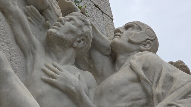 Rome, Italy – 11 January 2025. Detail from the Mazzini monument showing a muscular man reaching up with a soldier beside him in a helmet, both with uplifted gazes and strained expressions.