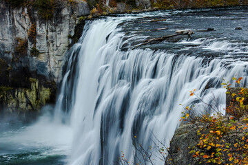 A powerful waterfall crashes over basalt cliffs, filling the canyon with swirling mist.
