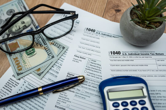 US dollar bills and form 1040 with glasses and calculator ready for 2026 tax processing - Powered by Adobe