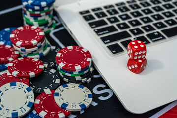 Stack of colorful poker chips near laptop keyboard representing online gambling, casino and poker games