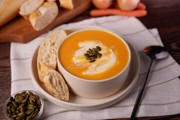 creamy pumpkin soup garnished with pepitas served with crusty bread and a touch of cream in a cozy rustic kitchen setting with soft natural light, gourmet, presentation, artistic, flavors, autumn