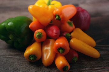 an inviting assortment of colorful bell peppers displayed on a rustic wooden table, showcasing a variety of vibrant hues including yellow, orange, red, and green, evoking a fresh and natural atmospher