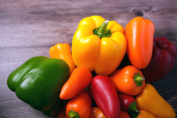 vibrant assortment of fresh colorful bell peppers and chilies on wooden surface displaying natural appeal and diversity in autumnal tones of yellow, orange, red, and green, edible, juicy, tempting