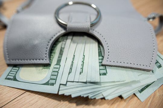 Grey handbag with many 100 cash dollars concept of financial freedom
