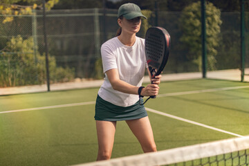 Padel tennis player with racket in action on the court. Woman athlete with paddle racket on court...