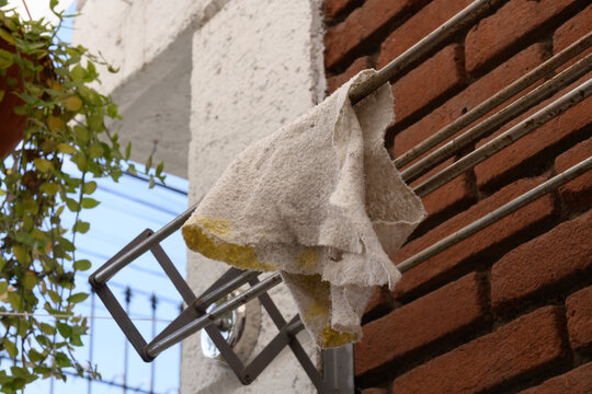 Old Rag Drying on Metal Clothesline Against Brick Wall - Powered by Adobe