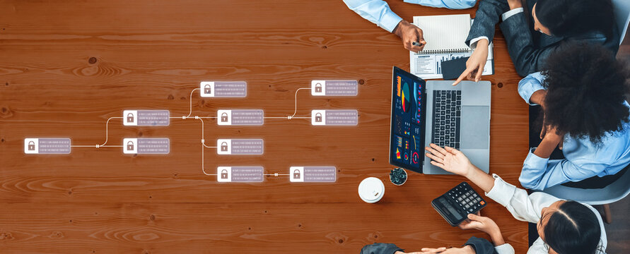 A diverse business team is engaged in a collaborative strategy meeting using a laptop for data analysis and project planning over a wooden desk. Trope - Powered by Adobe