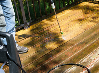 Using a pressure washer to clean the old finish off of a wooden deck
