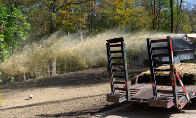 Hay being strewn over seeded topsoil as part of a landscaping job