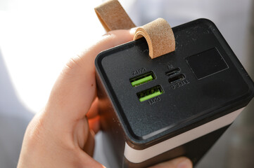 portable power bank with digital display and USB ports held in hand, concept of mobile charging, modern technology, portable energy source, and electronic device for everyday use and travel.