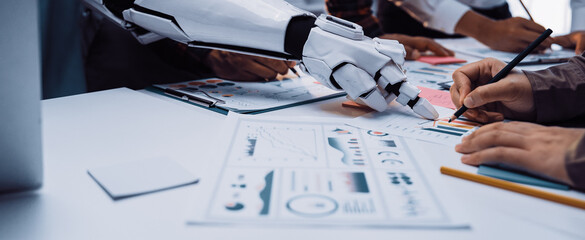 A futuristic scene depicting a robot arm collaborating with humans in an office. The team analyzes graphs and strategizes while utilizing modern tools and technology.Noogenesis