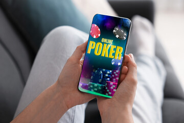Woman playing online poker on mobile phone at home, closeup