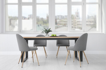 Table and chairs near big window in room. Interior design