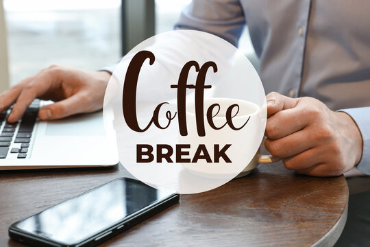 Coffee break time. Office worker with cup of hot drink using laptop at desk, closeup